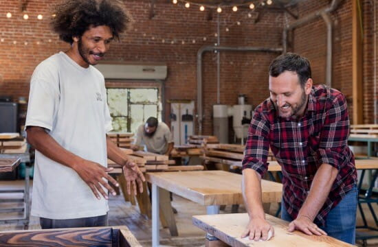 People smiling while working in a woodworking warehouse.