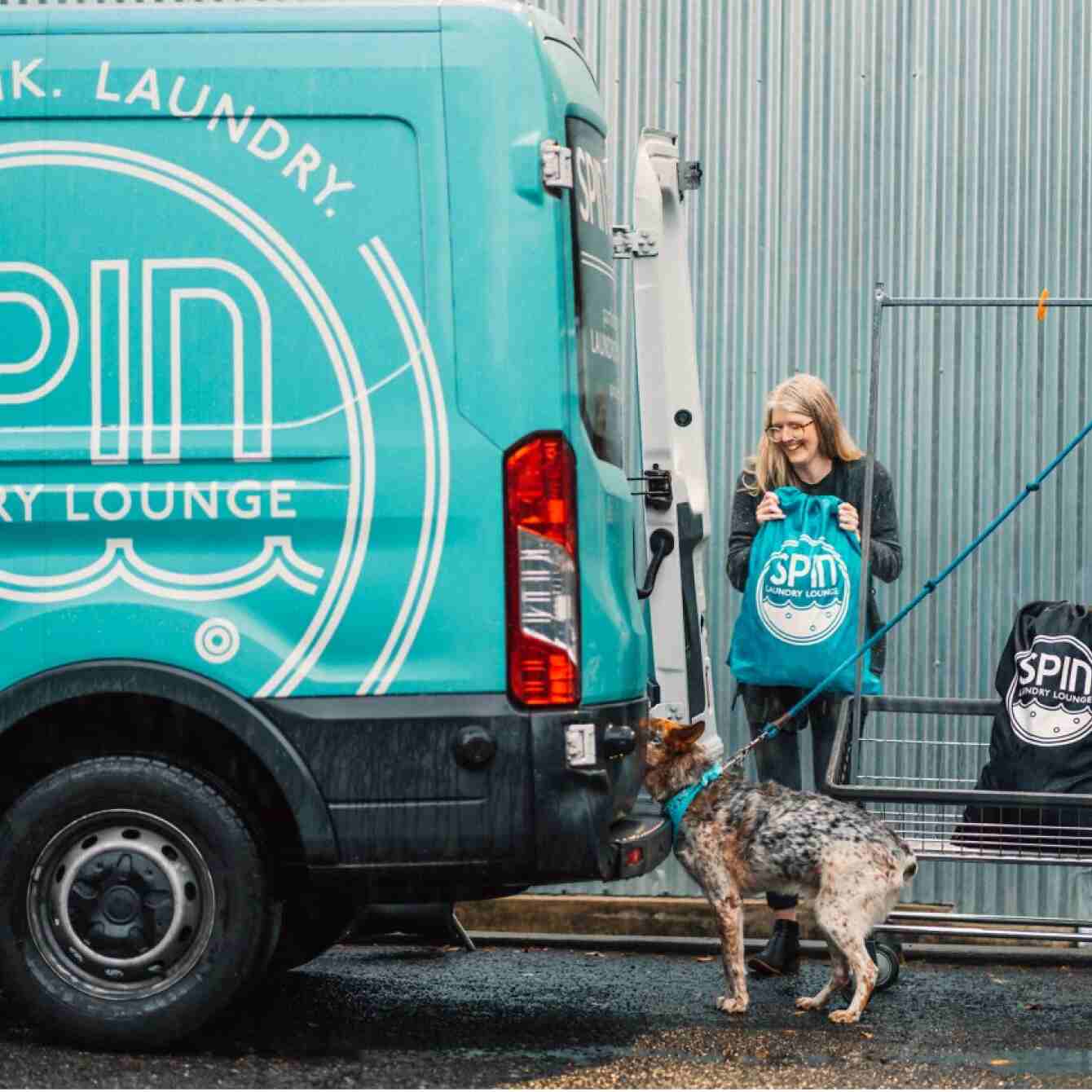 Health services business owner smiling with dog behind business van
